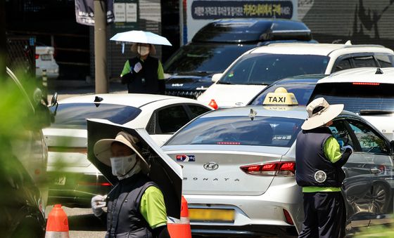모자 위에 양산…아스팔트 주차요원들 '땡볕과의 전쟁'