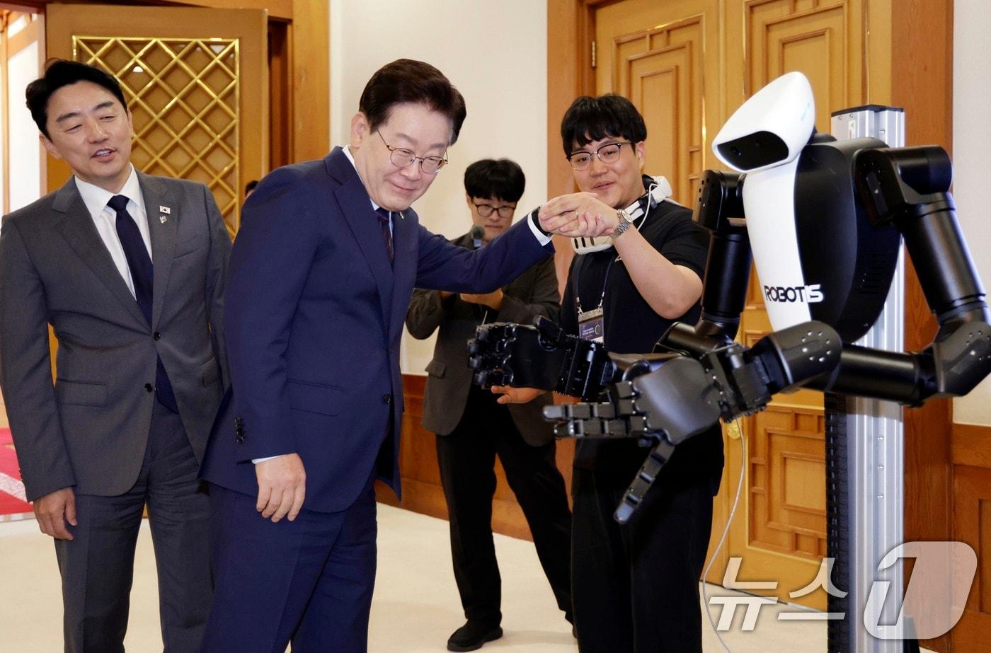본문 이미지 - 이재명 대통령이 26일 청와대에서 열린 미래 新안보 혁신기업 육성 전략회의에 참석해 휴머노이드 로봇을 살펴보고 있다. 2026.6.26 ⓒ 뉴스1 이재명 기자