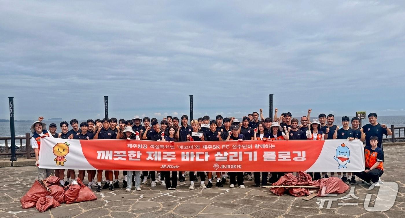 본문 이미지 - 제주항공 객실승무원 환경봉사단 에코머와 프로축구단 제주SK FC 선수단 및 코치진 등 총 50여명이 2일 제주 서귀포 논짓물해변에서 '플로깅'(Plogging) 해양 정화 활동을 펼친 뒤 기념 사진을 촬영한 모습(제주항공 제공). 2026.7.2.